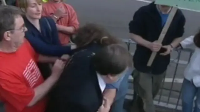 John Prescott tussles with a man who threw an egg at him. Remnants of the egg are visible on the left side of Prescott's suit. A man and a woman to the left of the frame try to separate them