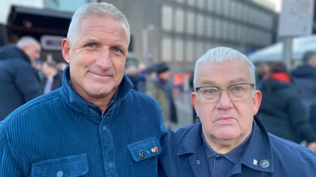 Gary Booth and and Michael Sefton. They are both wearing blue jackets and have badges on.