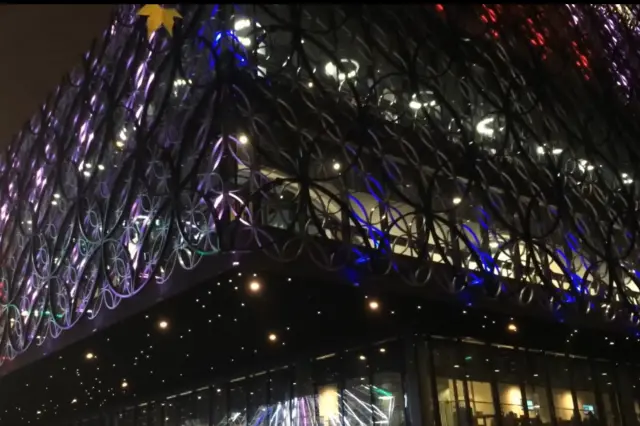 The outside of the library with the circular patterns on the exterior lit up in different colours