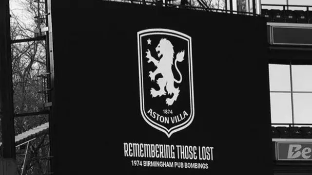 A big screen with Aston Villa's club badge and a caption underneath reading: Remembering those lost. 1974 Birmingham Pub Bombings. Stadium stands can be seen to the right