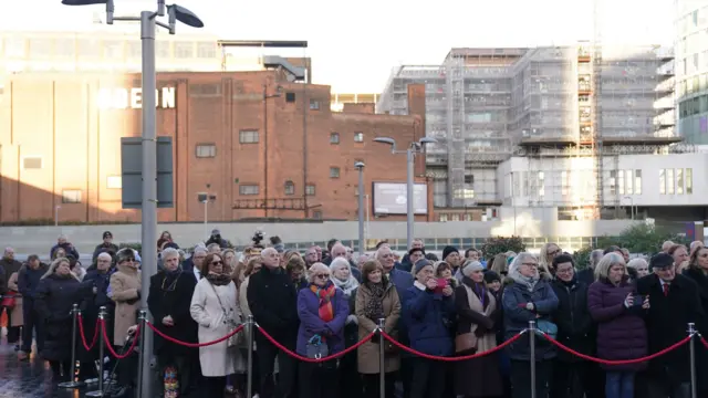 Crowds attending the service with a view of the city behind them