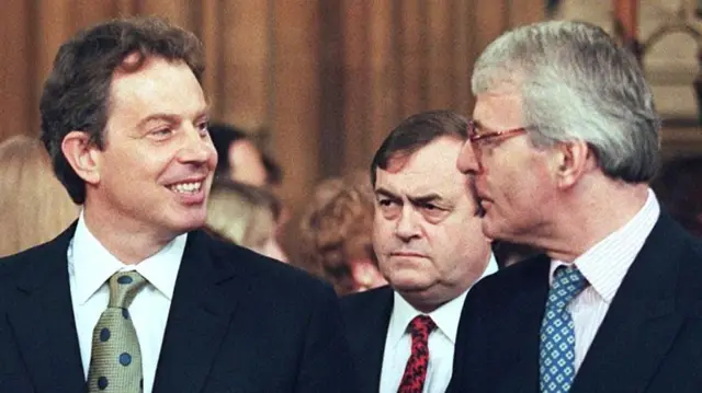 Tony Blair and John Major speaking while John Prescott stands behind the pair in the Commons in 1997