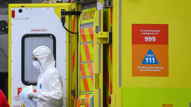 paramedic wearing personal protective equipment (PPE) exits an ambulance outside St Thomas" Hospital in Westminster