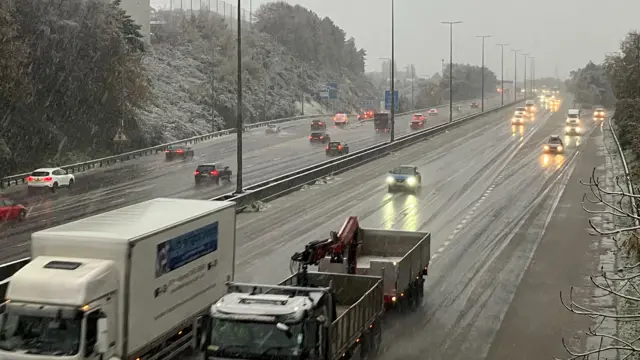 A multi-lane highway showing lorries and cars in snowy conditions