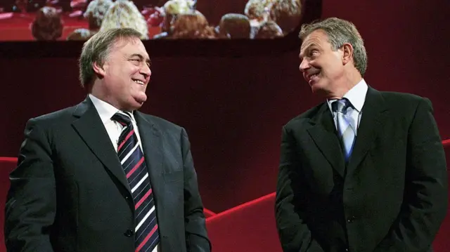 Lord Prescott and Tony Blair smiling together on stage