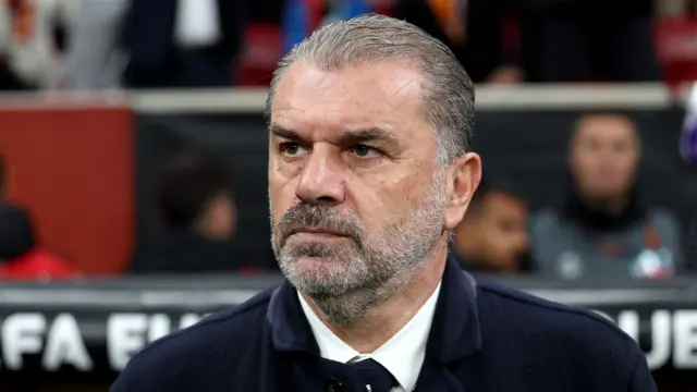 Manager Ange Postecoglou standing in front of the Tottenham dugout looking towards the pitch