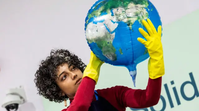 An activist holds a balloon in the form of the globe during a protest action at the COP29 United Nations climate change conference, in Baku, Azerbaijan