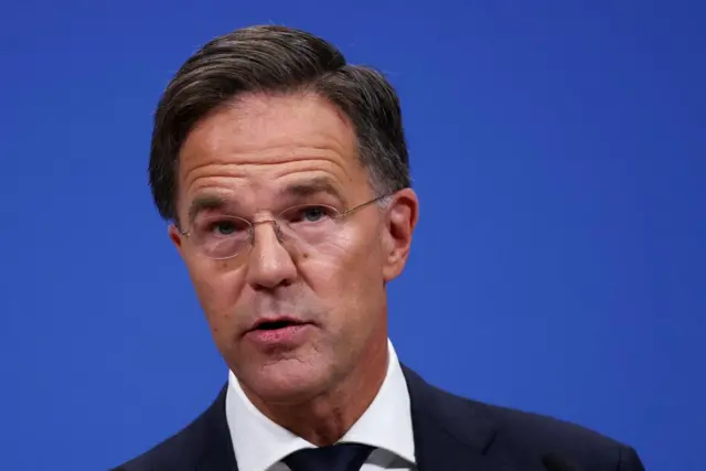 Shot of Mark Rutte, Nato chief and Dutch PM, from shoulders up, with blue background