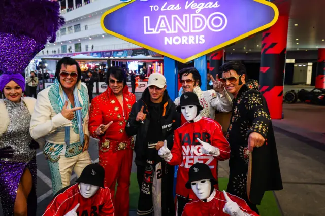 Lando Norris is greeted by performers in Las Vegas