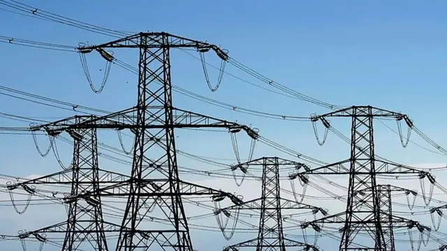 Multiple electricity pylons with a clear blue sky in the background