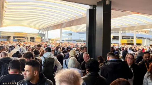 A large group of people standing outside Gatwick Airport's south terminal