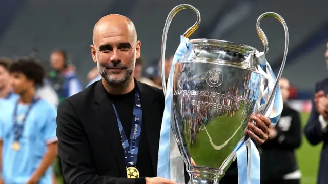 Manchester City manager Pep Guardiola holding the Champions League trophy in 2023