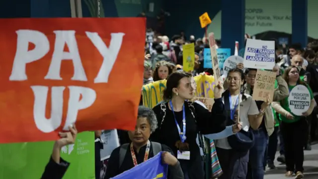 Activists gather with banners, including one that reads: "Pay Up," outside the plenary halls to voice their demands for a variety of climate-related issues, including labour rights, indigenous peoples' rights, loss and damage financing and the expulsion of fossil fuel lobbyists from the conference on day six at the UNFCCC COP29