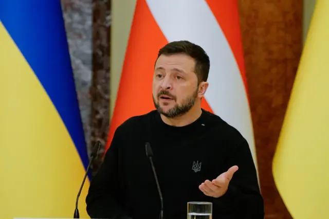 Ukraine President Volodymyr Zelensky speaking at a podium, gesturing with left hand, taken 19 Nov. Ukraine and Denmark flags behind him,