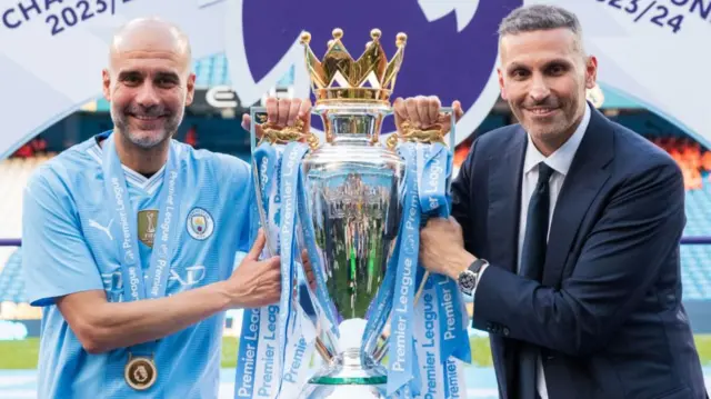 Pep Guardiola and Khaldoon Al Mubarak holding the Premier League trophy together in 2024