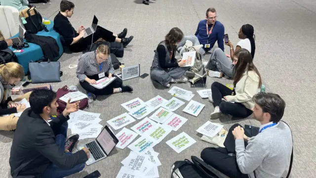 A group of activists sat on the floor with lots of paper signs