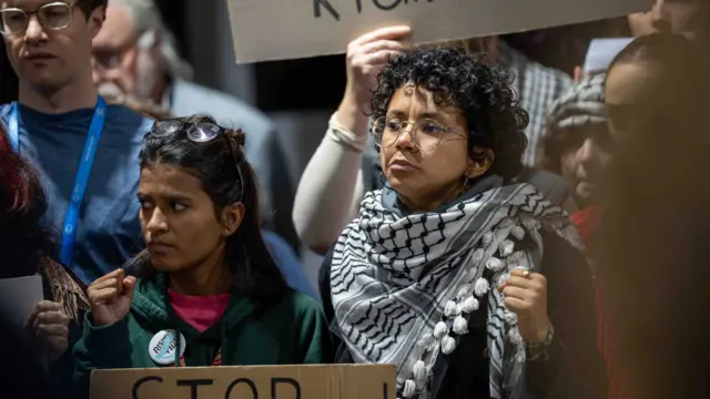 Group of protesters at COP29, holding up placards and with fists clenched