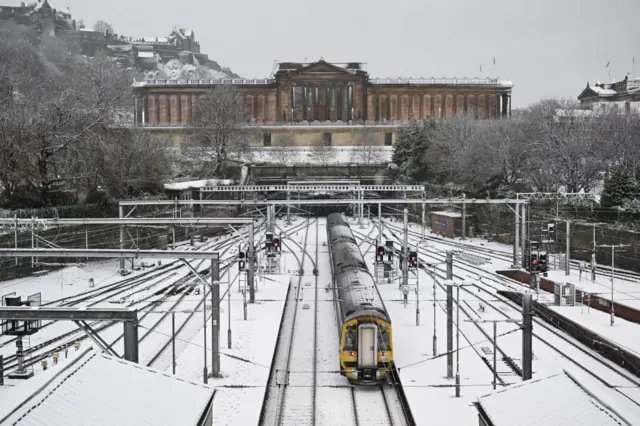 A train departs from Waverley Station through the snowfall during Storm Bert in Edinburgh