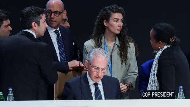 Key figures at COP29 gather around COP President, speaking to each other