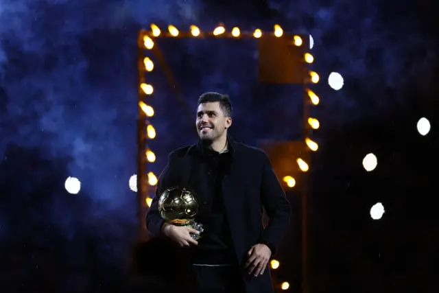 Rodri smiles as he holds his ballon dor up for the home fans