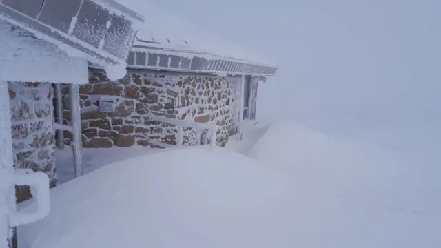 Drifts of deep snow outside the building. The walls and roof are also caked in ice.