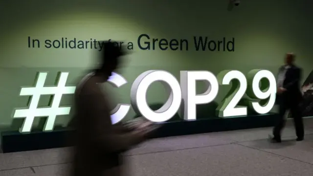 Participants walk past the COP29 logo during the United Nations Climate Change Conference (COP29) in Baku, Azerbaijan, on November 21, 2024.