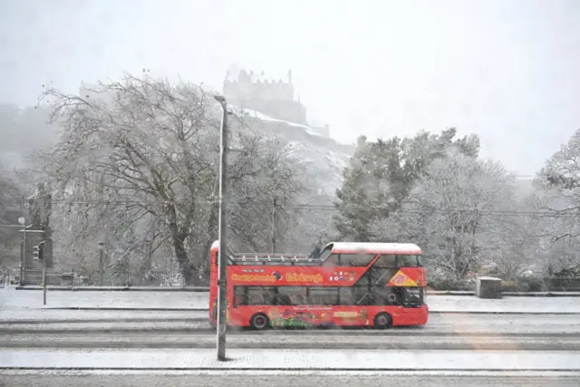 Tour bus in the snow on Princess Street in the shadow of Edinburgh Castle