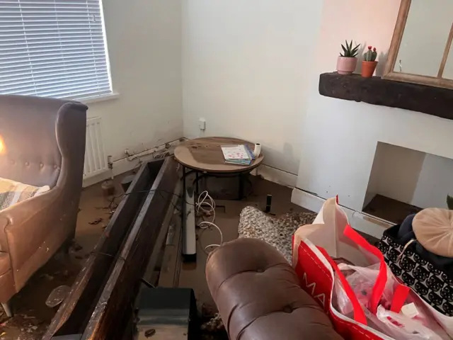 Water damage to a living room, showing a flooded coffee table, chair and sofa