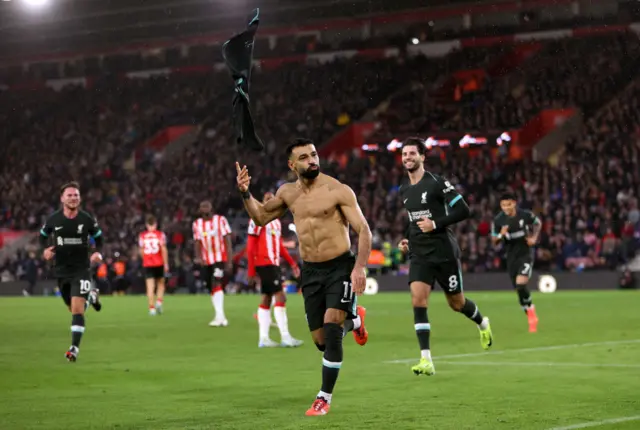 Salah throws his shirt in the air as he runs to celebrate his goal