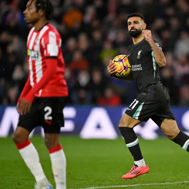 Salah fist pumps as he carries the ball back to kick off after scoring