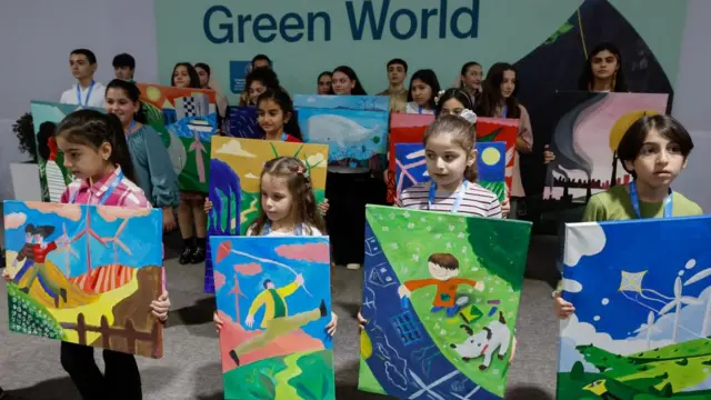 Child activists standing in rows holding up nature-themed paintings.