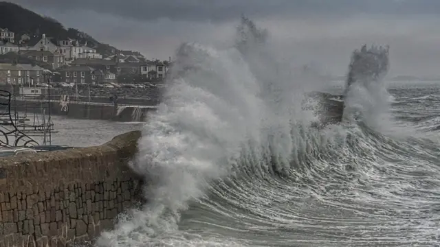 High wave crashes into stone wall in Mousehole, Cornwall