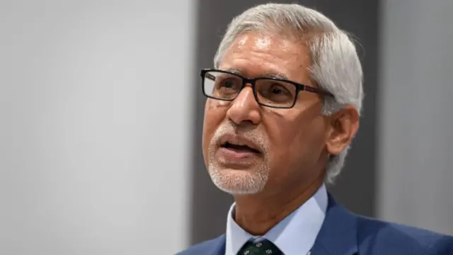 Jagan Chapagain, secretary general of the International Federation of Red Cross and Red Crescent Societies, shot from chest height up. In blue suit, looking to left, wearing dark rimmed glasses and a badge with the Red Cross and Red Crescent symbols on his right lapel.