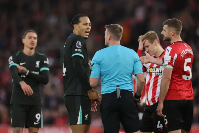 Players from both sides surround the referee