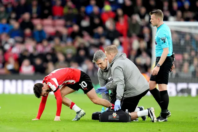 Lallana stretches his hamstring with the physio