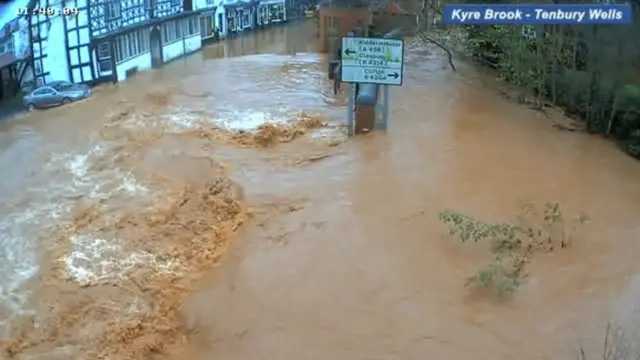 Camera footage captures flood water gushing through a flood wall.