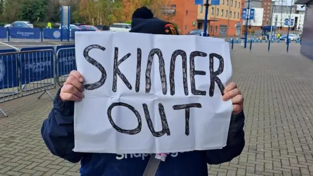 A fan holds a 'Skinner Out' sign