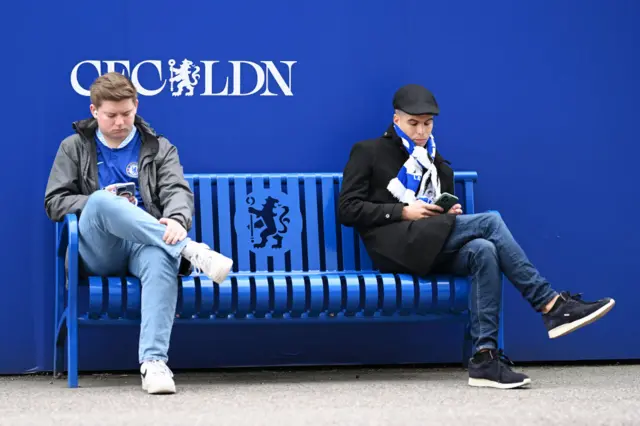 Two Chelsea fans looking at their mobile phones