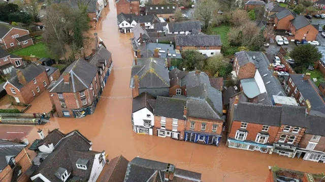 Several houses submerged in brown, murky flood water.