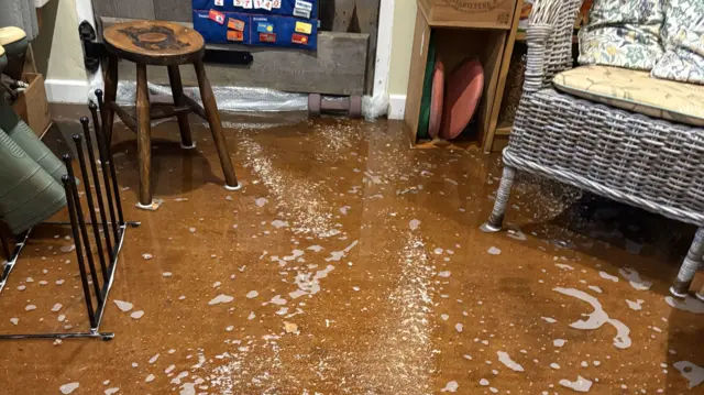 A living room submerged in two inches of flood water