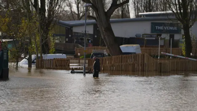 Man walks through flood water at Billing Aquadrome in Northamptonshire.