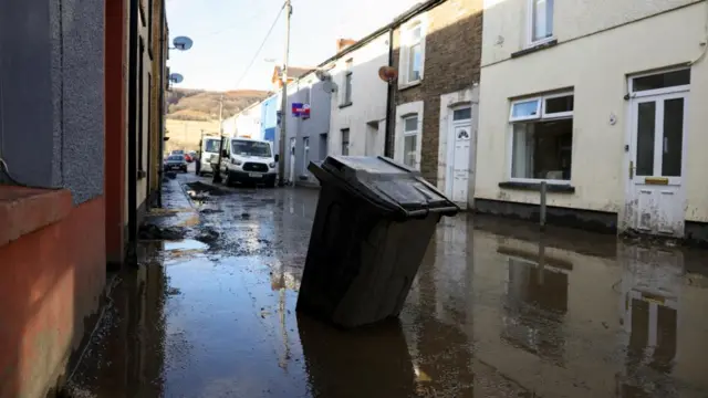 A view shows a partially submerged rubbish bin on a mud-covered street, in the aftermath of Storm Bert, in Cwmtillery, South Wales