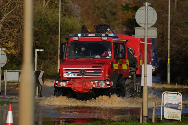 A red emergency services vehicle wades through water that is just above ankle height near Billing Aquadrome