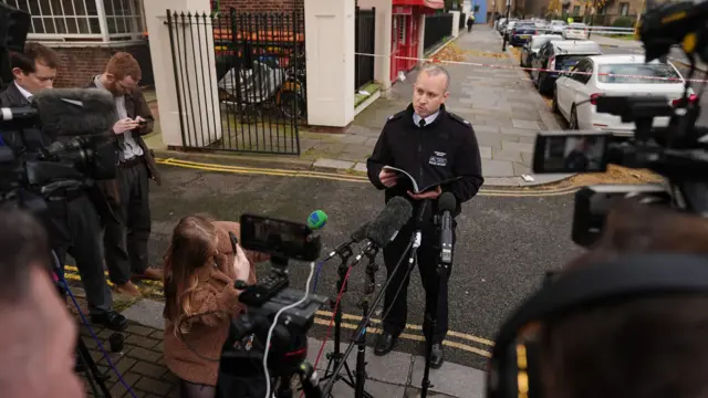 A police officer gives an update in front of media on the corner of a road