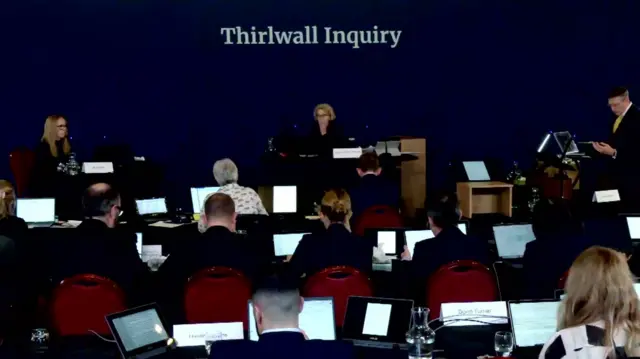 Inquiry room with Alison Kelly sat opposite counsel to the inquiry Nick De la Poer with numerous people looking at computer screens in the foreground