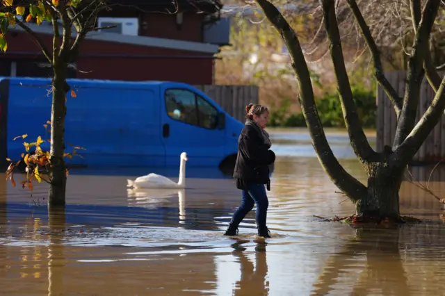 A woman walks through floodwater near the Billing Aquadrome in Northamptonshire.