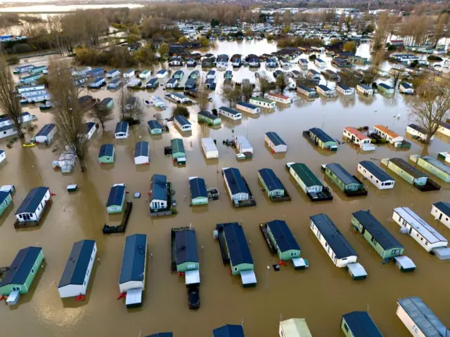 Rows and rows of caravans sit in brown flood water