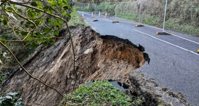 A landslide is seen in Northern Ireland. A large portion of the road is seen taken out with mud on the side.