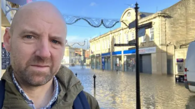 BBC news editor Neil Beck taking a selfie in front of the flooded Chippenham high street