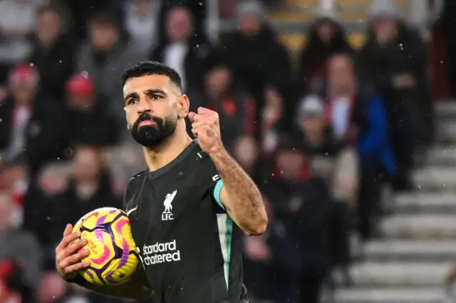 Mohamed Salah holds the ball and celebrates